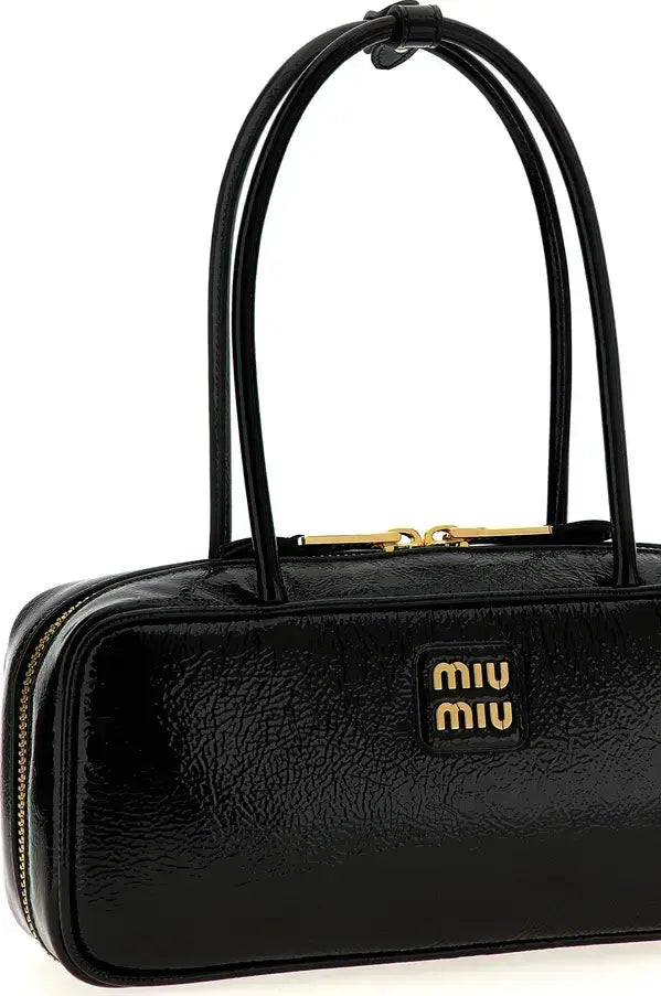 A black textured leather Miu Miu handbag with gold-tone hardware and a prominent gold logo patch on the front, set against a plain white background.