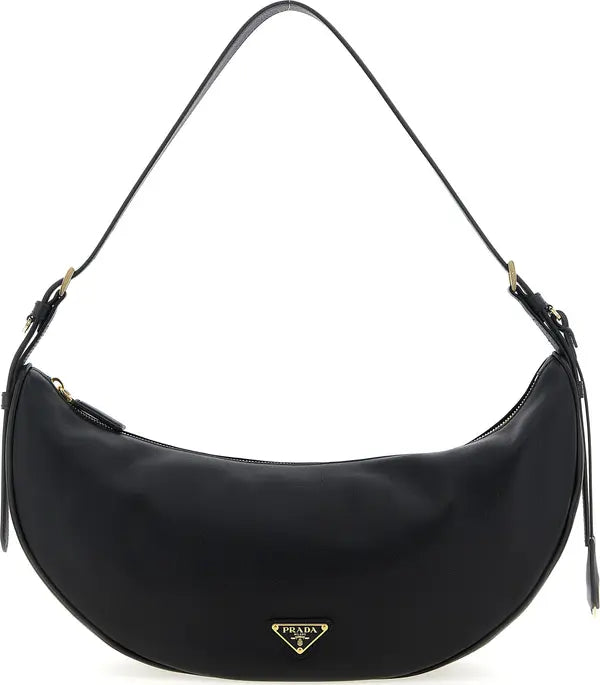 A black Prada crescent-shaped shoulder bag with a gold-tone triangular logo plaque on the front and a thin black shoulder strap, shown against a plain white background.