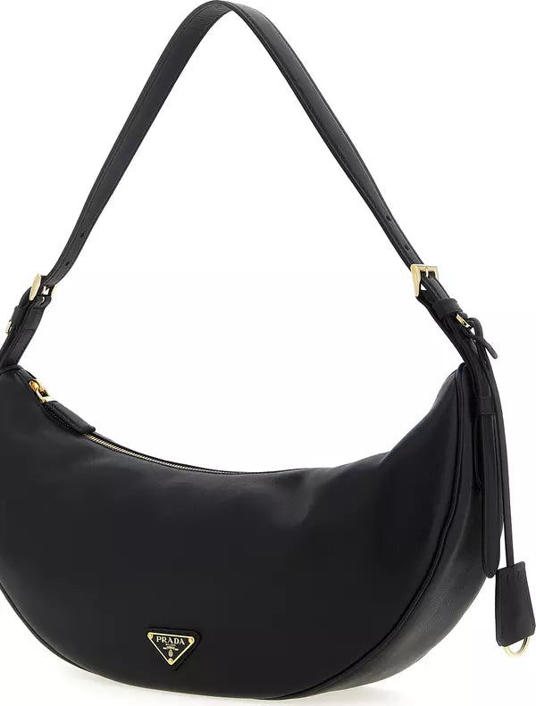 A black Prada crescent-shaped shoulder bag with gold-tone hardware and the signature triangular Prada logo plaque on the front, set against a plain white background.