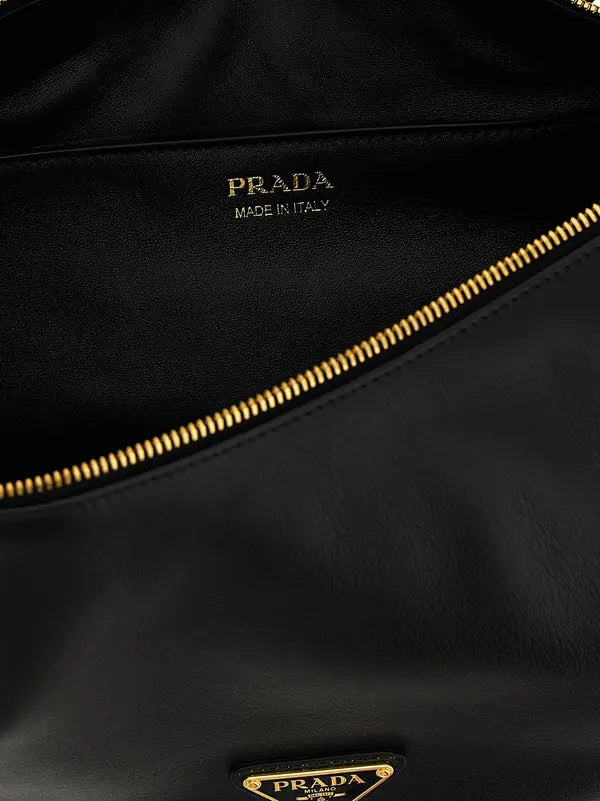 Close-up of a black leather Prada bag interior showing the gold-tone zipper, gold &