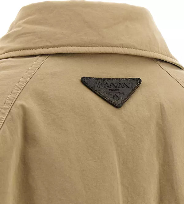 Close-up of a beige jacket with a dark brown triangular leather patch on the back, featuring the embossed brand name &