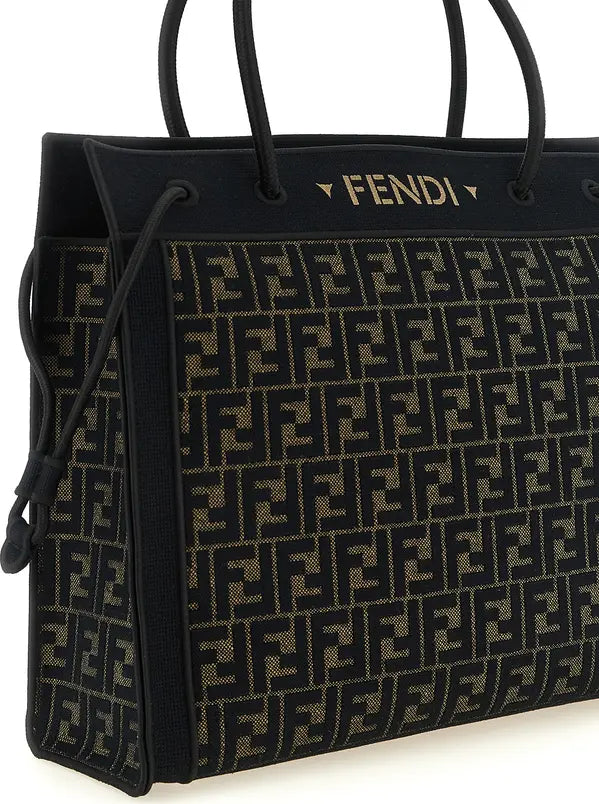 Fendi black and brown Zucca monogram canvas tote bag with black leather handles and a gold Fendi logo on the top, shown on a white background.