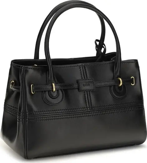 A black faux-leather handbag with double top handles, gold-tone hardware, and a small central brand plaque reading &