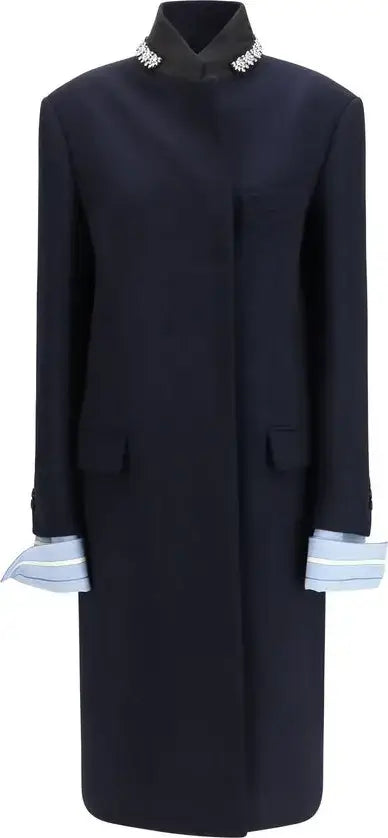 A dark navy blue long coat with a high collar featuring silver rhinestone trim, front flap pockets, and light blue and white striped cuffs.