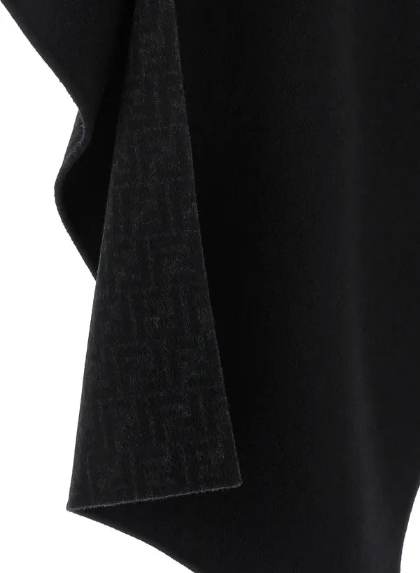 Close-up of a black draped garment or fabric with a subtle tonal monogram-like texture, shown against a white background.