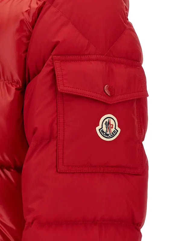 Close-up of a red puffer jacket sleeve with a front flap pocket and a circular embroidered Moncler logo patch on the pocket.