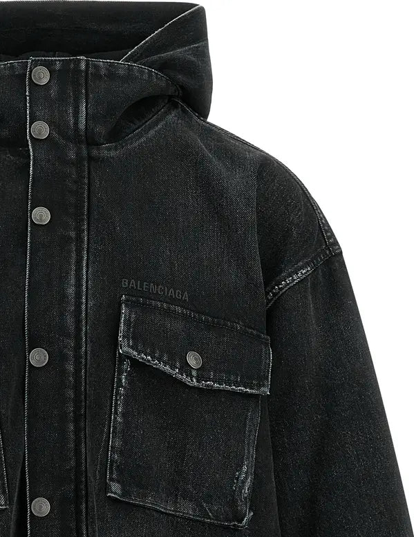 Close-up of a black washed denim hooded jacket with a button front, chest pocket, and visible Balenciaga text on the pocket flap, set against a plain white background.