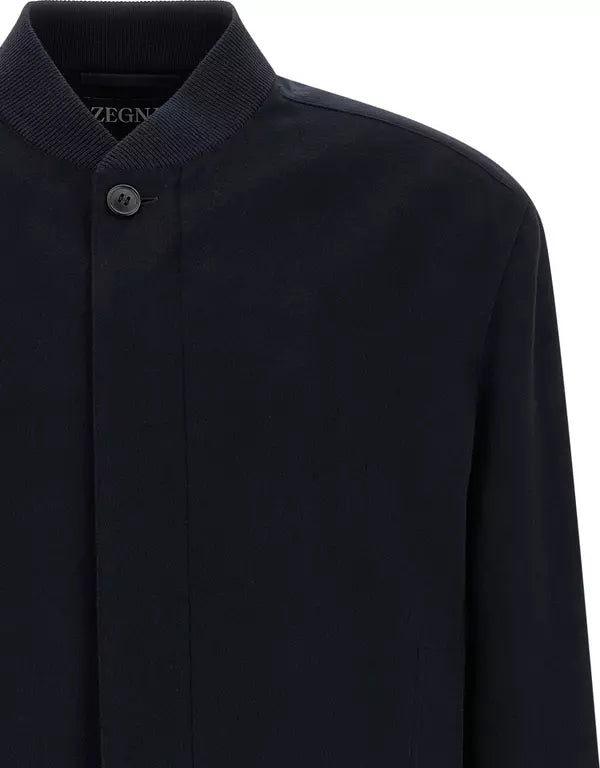 Close-up of a dark navy long-sleeve knit jacket with a ribbed stand collar and a single button closure, showing the Zegna brand name on the inner neck label.