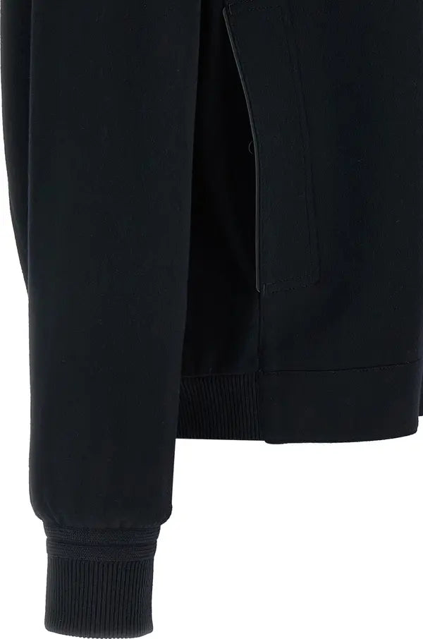 Close-up of a black long-sleeve knit top or sweater showing the sleeve cuff, side seam, and ribbed hem against a white background.