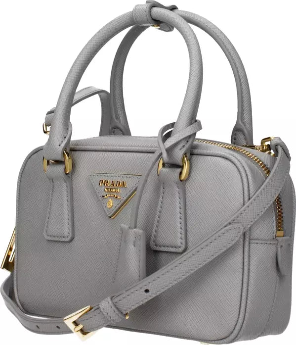 A light gray textured leather handbag with gold-tone hardware, featuring dual top handles, a detachable shoulder strap, and a gold-tone triangular Prada logo plaque on the front.