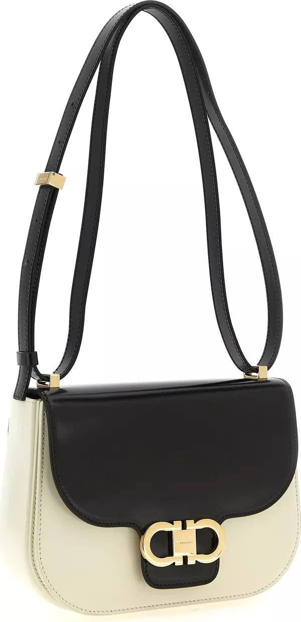 A color-blocked leather shoulder bag with a black top flap, black strap, and cream-colored body, featuring a gold-tone metal &
