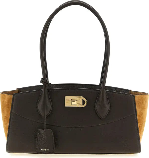 A Salvatore Ferragamo leather handbag in black with tan suede side panels and a gold-tone turn-lock clasp, shown on a plain white background.