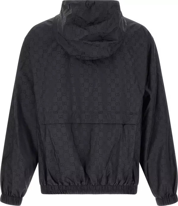 A black hooded windbreaker jacket featuring an all-over tonal interlocking monogram pattern, shown from the back against a plain white background.