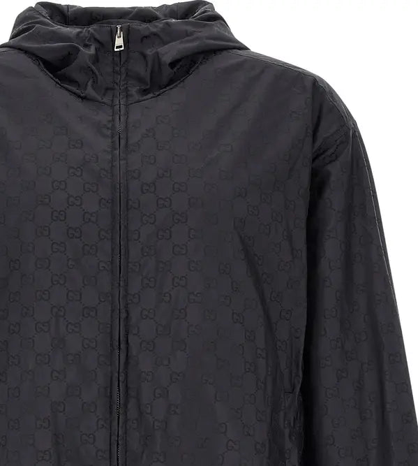 A close-up of a black hooded jacket featuring an all-over tonal interlocking GG monogram pattern, a front zipper, and a silver zipper pull, set against a plain white background.