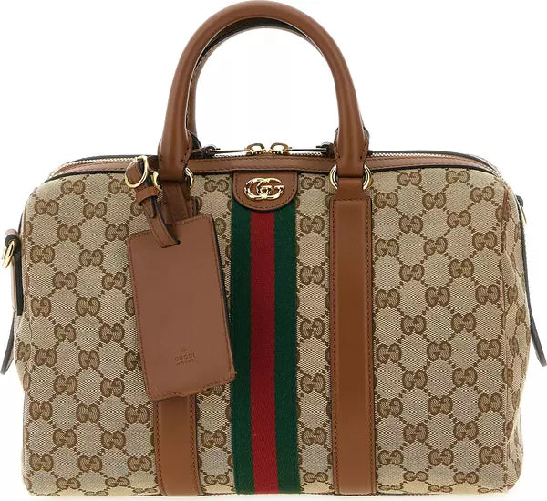 Gucci GG Supreme canvas duffel bag with brown leather handles and web stripe, featuring gold-tone hardware and a hanging leather tag on a white background.