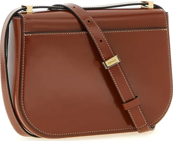 A brown leather shoulder bag with a structured, rounded rectangular shape, featuring a matching leather strap with a gold-tone &