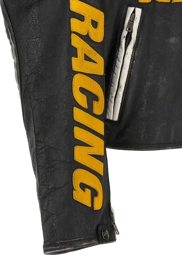 Close-up of a black leather jacket sleeve featuring large yellow &