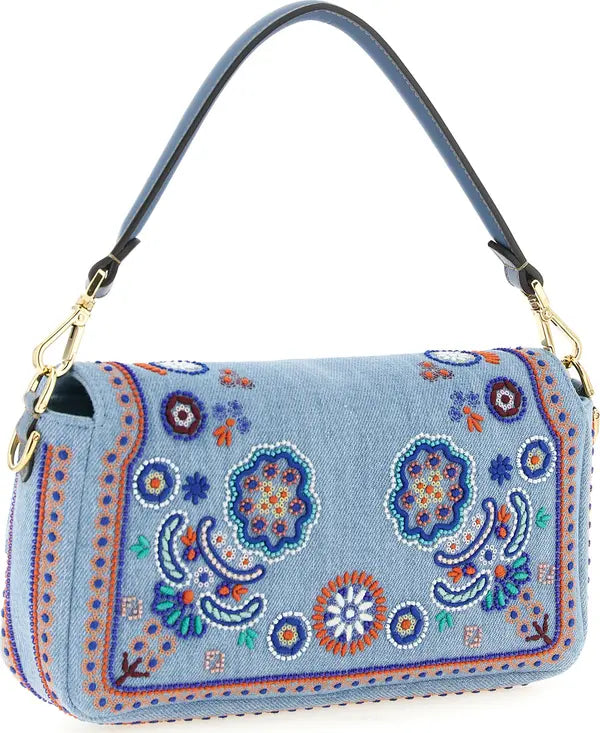 A light blue denim shoulder bag with colorful embroidered paisley and floral patterns, featuring a black leather strap and gold-tone hardware, set against a plain white background.