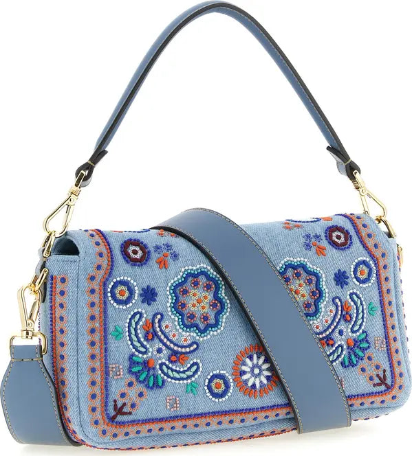 A light blue denim shoulder bag with colorful embroidered paisley and floral patterns, featuring a matching blue leather strap and gold-tone hardware, shown on a white background.
