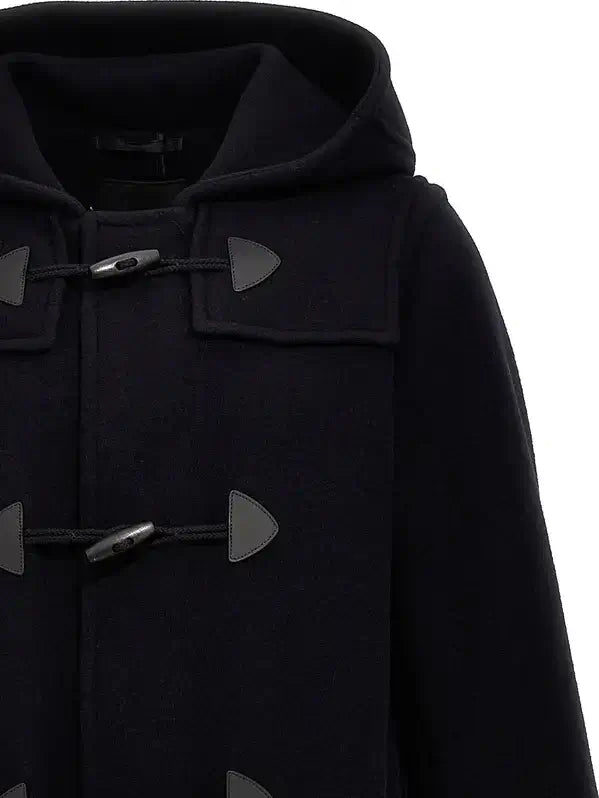 Close-up of a black hooded duffle coat with dark toggle closures and dark triangular tab accents, shown against a plain white background.