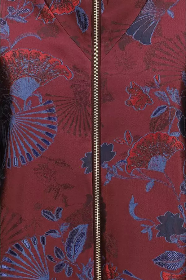 Close-up of a red patterned jacket with a central gold zipper, featuring a woven design of blue and red ginkgo leaves and fan motifs.