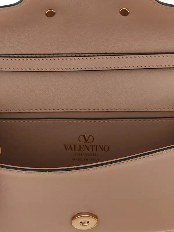 Close-up of the interior of a Valentino Garavani handbag in beige leather, showing the brand name embossed on the lining and gold-tone hardware.