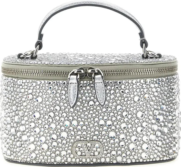 A silver rhinestone-covered top-handle handbag with a zip-around closure, double front hardware, and a visible Valentino V logo at the bottom center, shown on a plain white background.