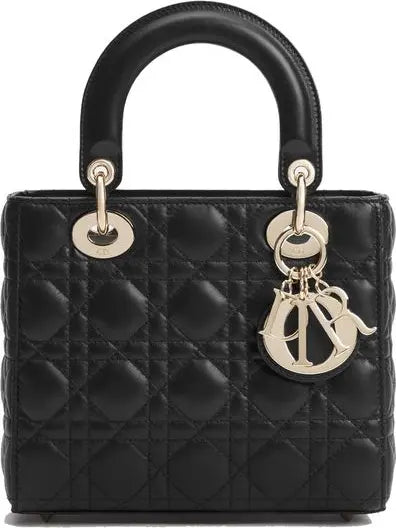 A black quilted leather top-handle handbag with gold-tone hardware and a hanging Dior logo charm, shown against a plain white background.
