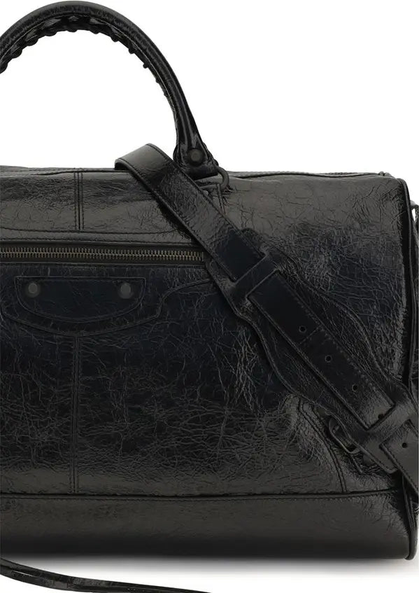 A close-up of a black distressed leather shoulder bag with a top handle and an adjustable shoulder strap, set against a plain white background.
