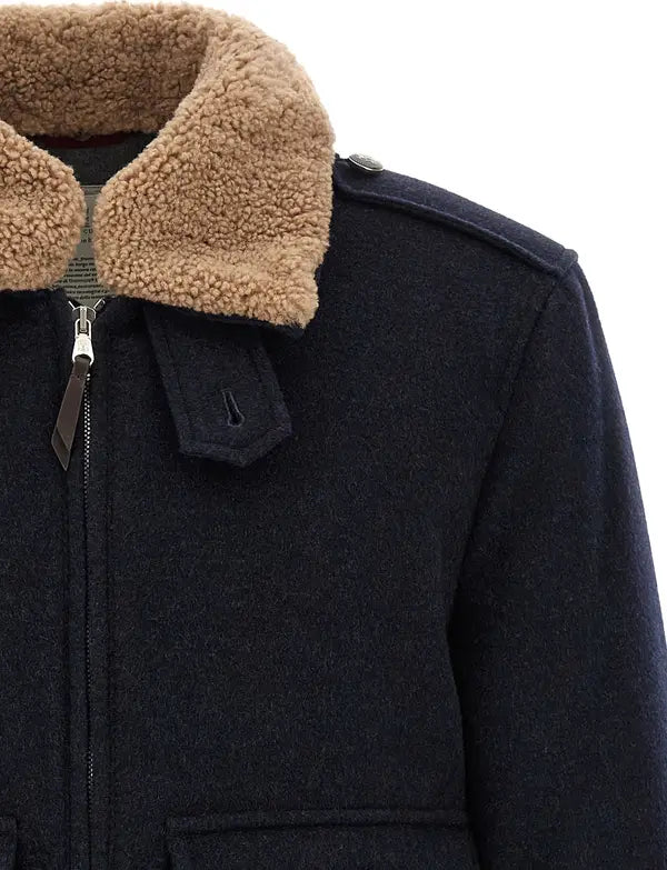 Close-up of a dark navy wool jacket with a tan sherpa fleece collar, featuring a front zipper, shoulder epaulettes, and a pocket tab.