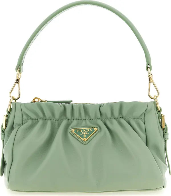 A sage green Prada nylon shoulder bag with gold-tone hardware and the signature triangular Prada logo plaque on the front, set against a plain white background.