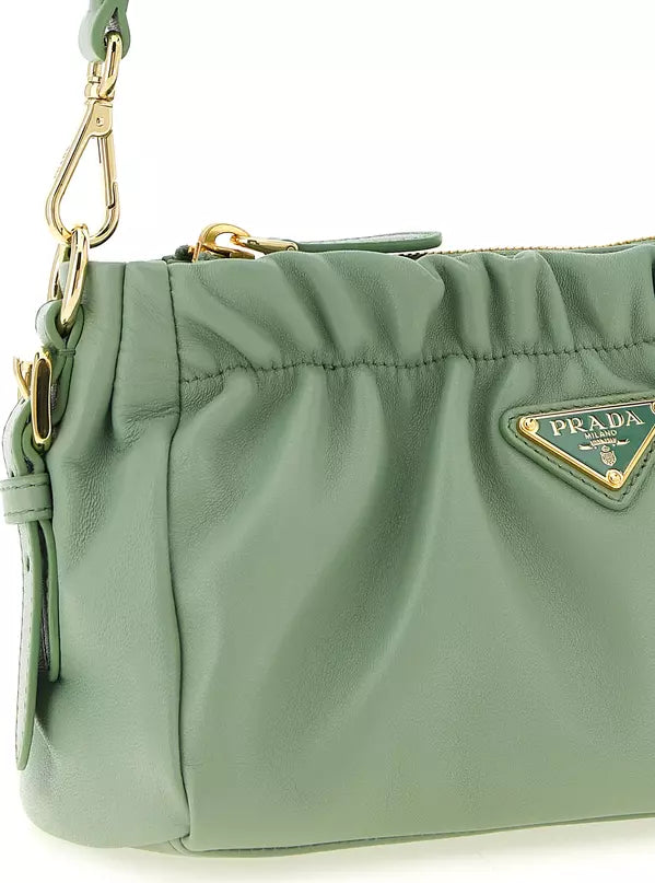 A sage green Prada shoulder bag made of textured leather, featuring a gold-tone triangular Prada logo plaque on the front and a gold-tone clasp on the strap.