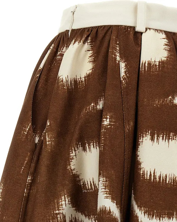 Close-up of a pleated skirt with a brown and cream ikat-style pattern and a cream waistband.