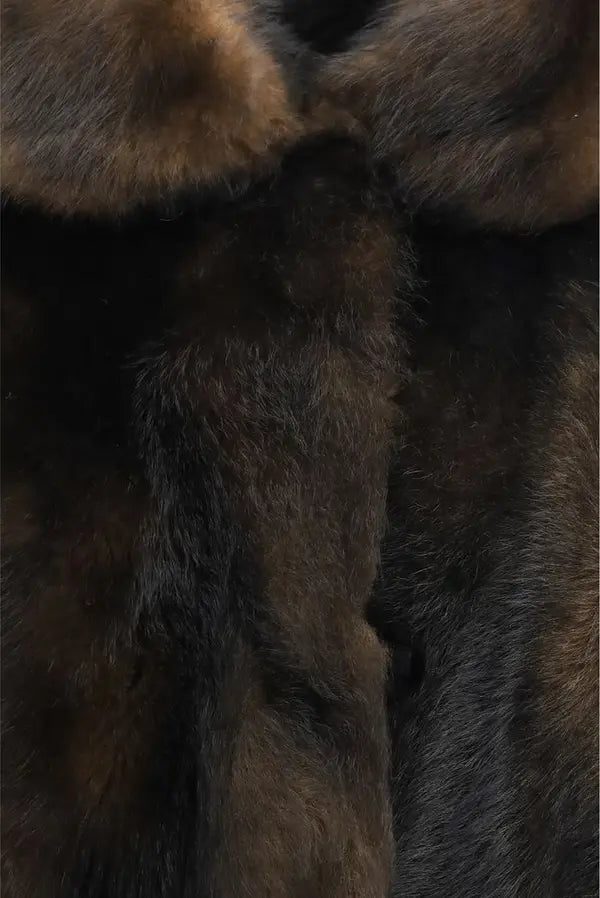 Close-up of dark brown and black fur texture, likely a coat or garment material, filling the frame.