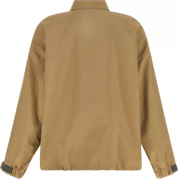A tan utility jacket shown from the back, featuring a relaxed fit, a pointed collar, and elasticized cuffs with dark gray accent tabs.