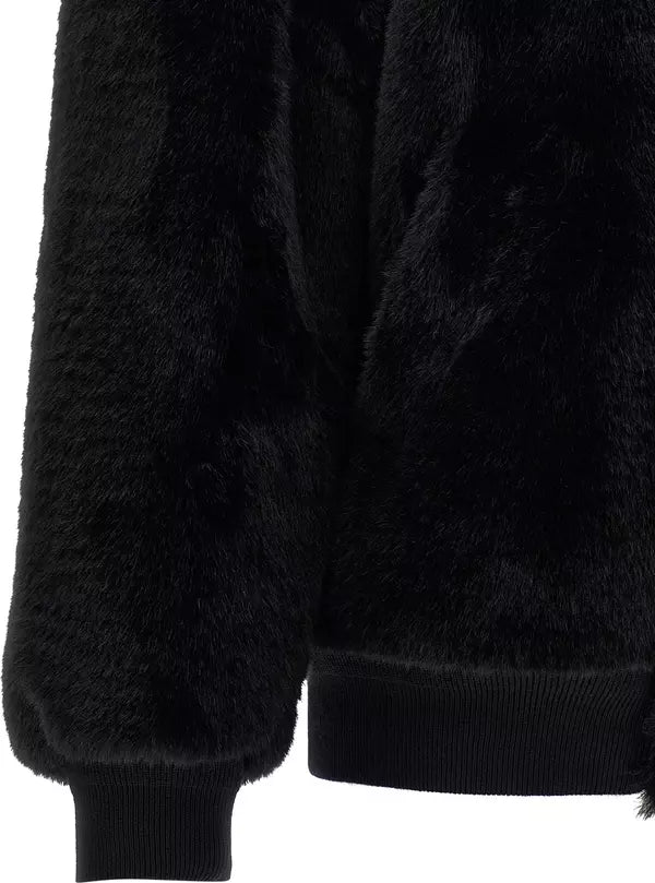 Close-up of a black faux-fur jacket or sweater showing the textured fabric and ribbed cuffs on a white background.