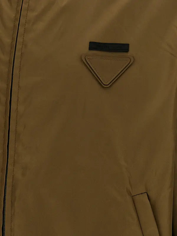 Close-up of a tan-brown jacket featuring a triangular patch logo on the chest and a black zipper track.
