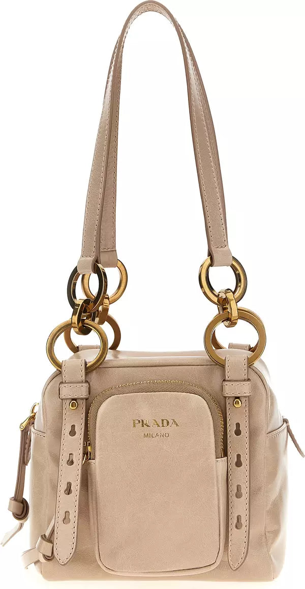 A Prada shoulder bag in light beige leather with gold-tone hardware, featuring a front zip pocket with the Prada logo and a long shoulder strap.