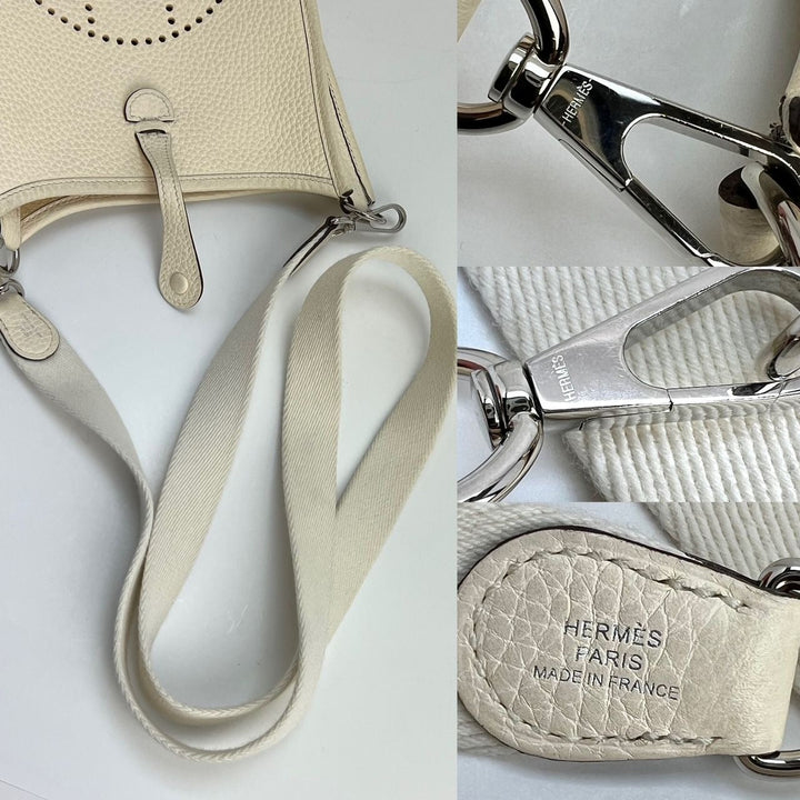 Close-up of a beige leather keychain with strap and silver hardware, featuring the Hermès logo.