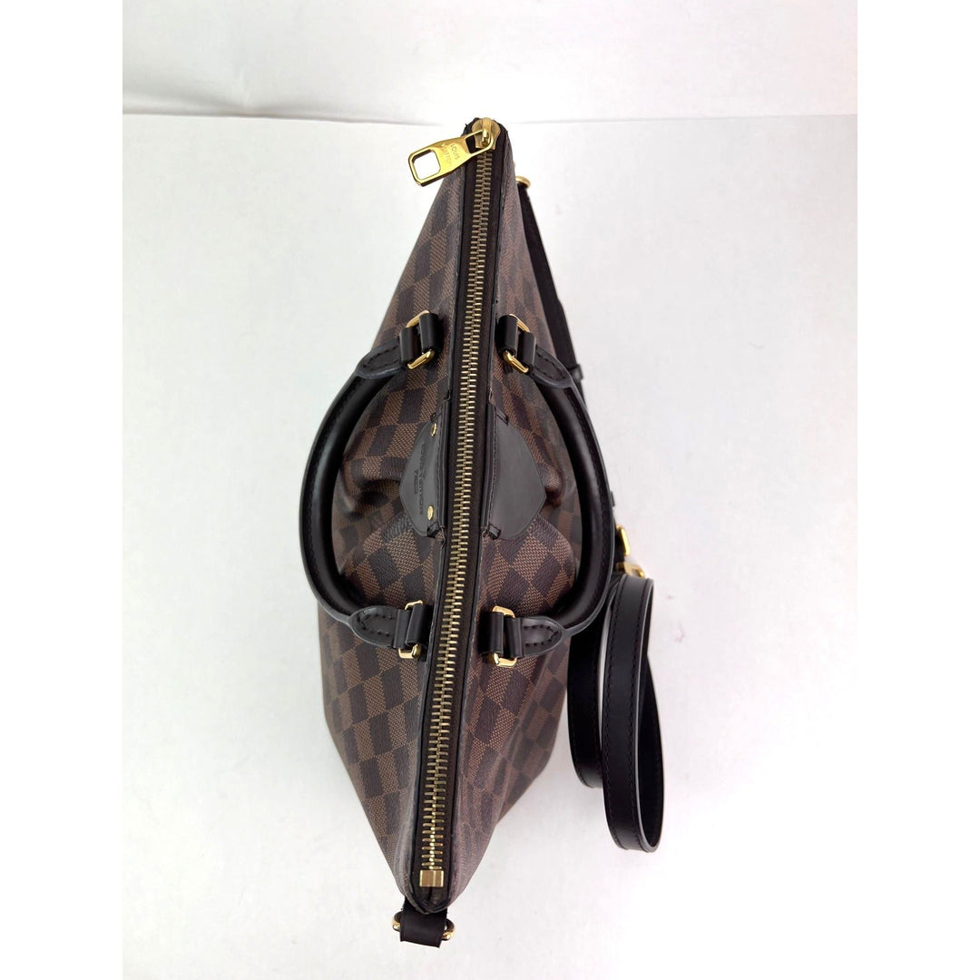 Brown checkered bag with black strap on a white background