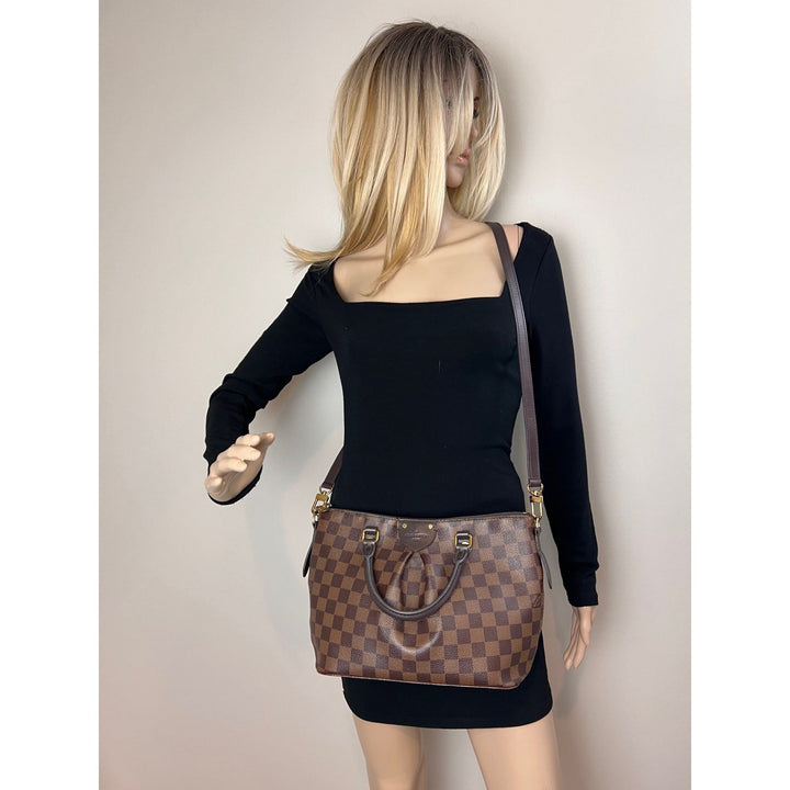 Woman wearing a brown checkered handbag on a plain background