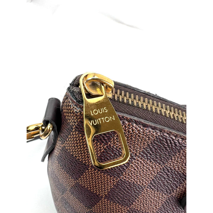 Close-up of a Louis Vuitton bag with gold zipper pull on a white background