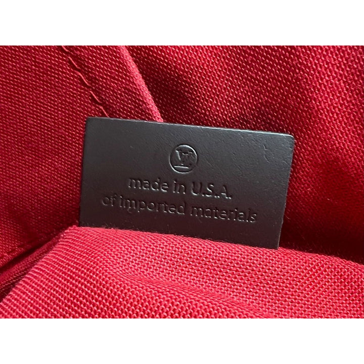 Black label on red fabric indicating 'made in U.S.A. of imported materials'.