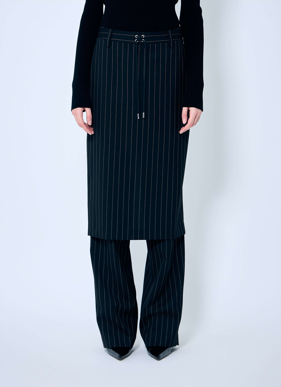 Person wearing a black pinstripe skirt and pants on a white background