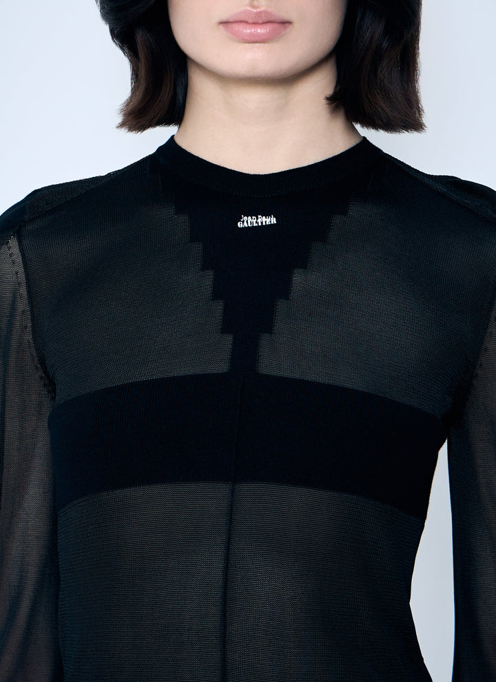 Person wearing a black outfit with a brand logo on a light gray background
