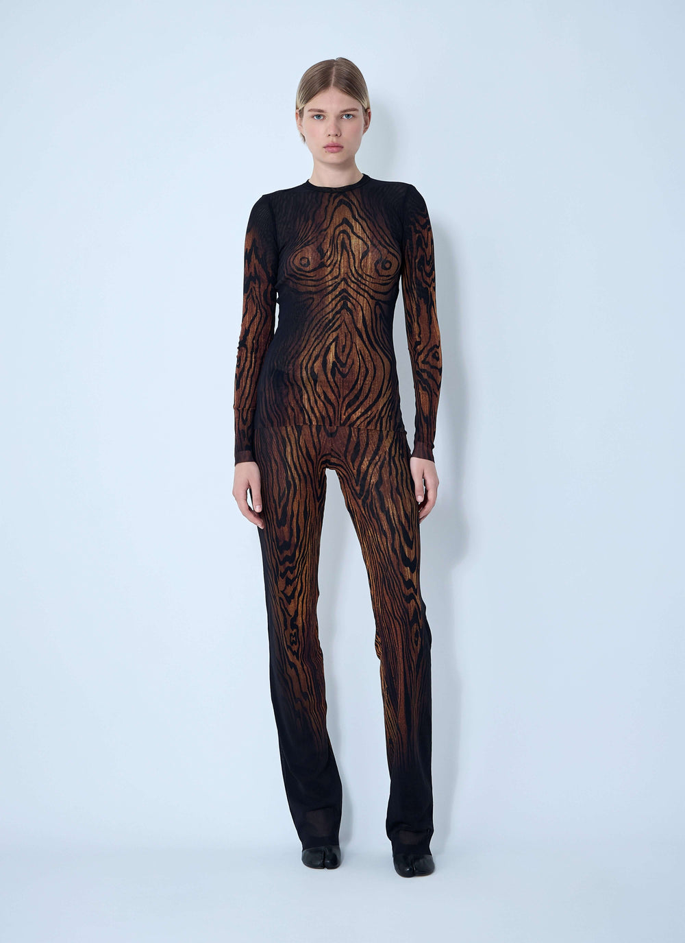 Model wearing a black and brown patterned outfit on a white background