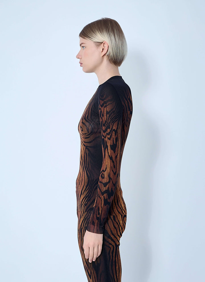 Person wearing a black and brown patterned dress against a white background