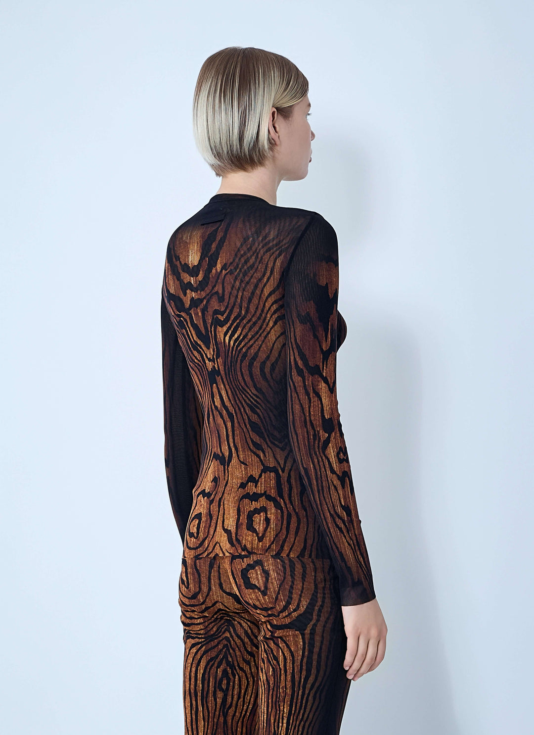 Person wearing a black and brown patterned dress against a white background