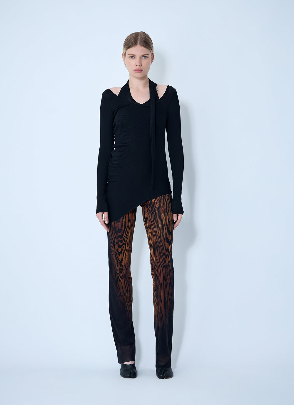 Woman wearing a black outfit with a unique pattern on a light blue background