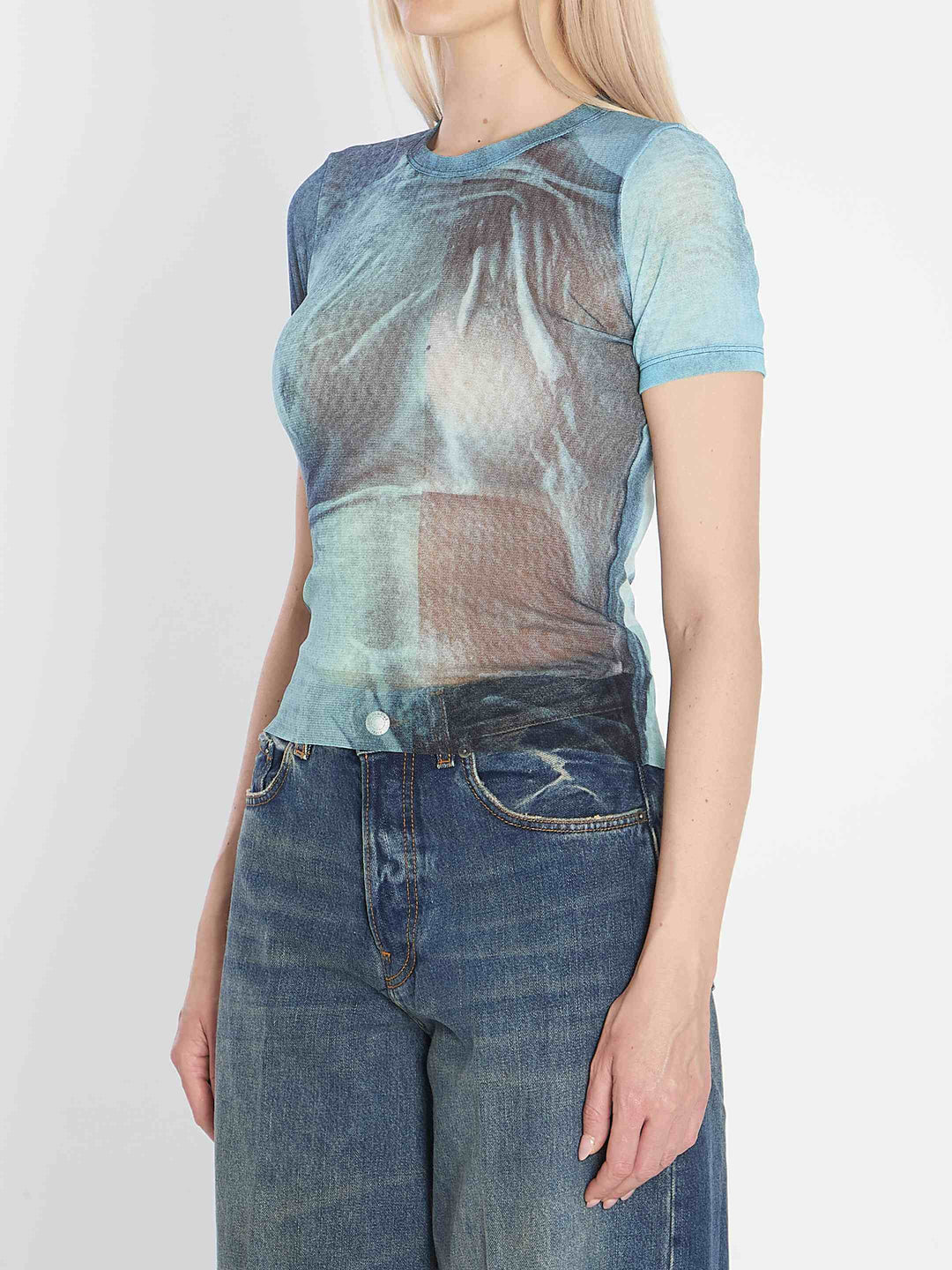 Person wearing a sheer blue top and jeans on a white background